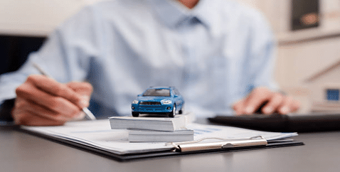 Person sitting at a desk signing an auto loan